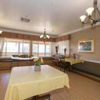 A well-lit dining room with yellow tablecloths and flower centerpieces.