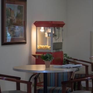 A cozy waiting area featuring a popcorn machine, table with chairs, and decor.
