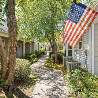 A peaceful residential pathway with an American flag displayed under the shade of trees.