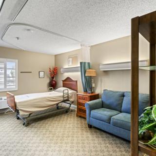 A well-furnished hospital room with a patient bed and a sofa.