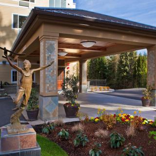 A hotel entrance featuring a decorative statue and well-maintained landscaping.