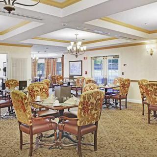 A well-decorated dining room with multiple tables and comfortable chairs, featuring elegant light fixtures.