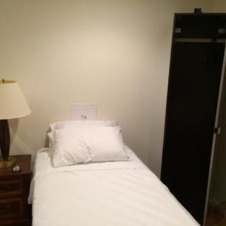 A minimalist bedroom with a single bed, nightstand, and wardrobe.