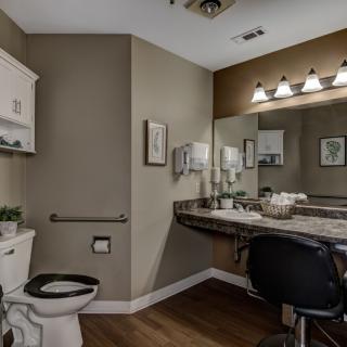 A modern bathroom with a large mirror, vanity lights, and elegant decor.