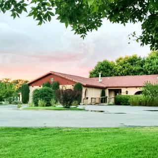 A suburban house with a red roof at sunset, surrounded by trees and a lush green lawn.