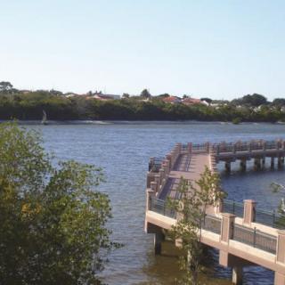 A scenic view of a river with a pier extending over the water, surrounded by lush greenery.