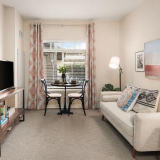 A cozy living room with a sofa, small dining area, and a TV.