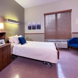 A cozy hospital room featuring a single bed, modern decor, and warm lighting.