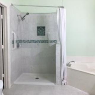 A bathroom with a tiled shower and a curtain next to a bathtub.