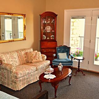 A cozy living room with a floral sofa, blue armchair, and wooden furniture accents.