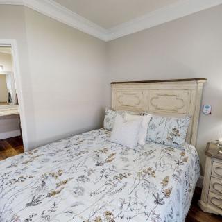A cozy bedroom with a bed featuring floral patterned bedding and a nightstand beside it.