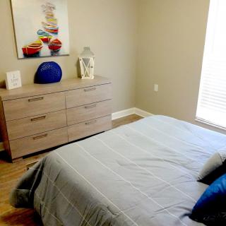 A neatly arranged bedroom with a bed and a wooden dresser.