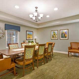 A well-lit dining room with a large table, chairs, and decorative artwork on the walls.