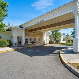A large building entrance with an extended covered driveway on a sunny day.