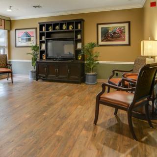 A cozy living room with a television, wooden flooring, and comfortable seating.