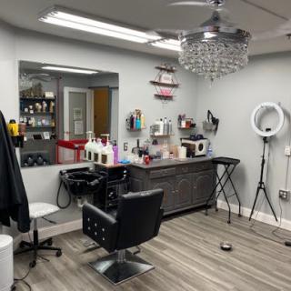 A modern hair salon featuring a stylish barber chair, elegant chandelier, and organized styling products.