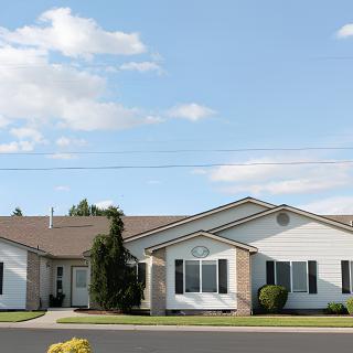 A suburban house with a clear blue sky and scattered clouds.