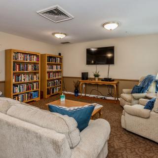 A cozy living room with sofas and bookshelves, featuring a wall-mounted television.