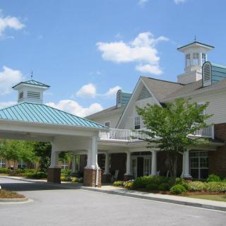 A building with a covered entrance and blue rooftops surrounded by greenery.