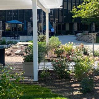 A lush garden area with a white pergola and bench provides a peaceful outdoor space.