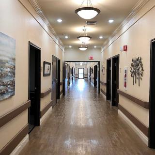 A well-lit hallway with multiple doors and artwork on the walls.