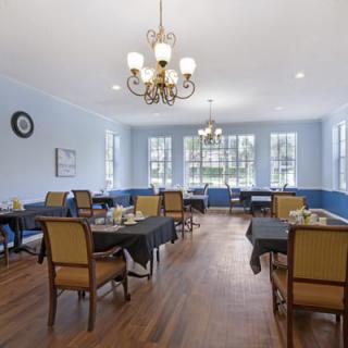 A spacious dining room with elegant furnishings and a chandelier.