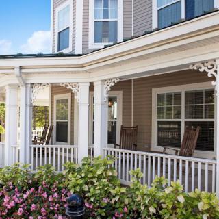 A charming house with a wraparound porch and a blooming garden.