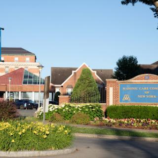 A view of a modern building surrounded by well-maintained gardens and a clear blue sky.