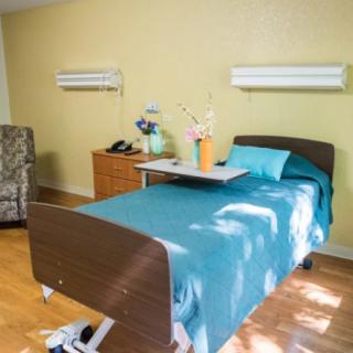 A clean and organized hospital room with a single bed and medical equipment.