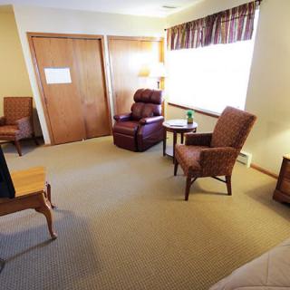 A cozy living area with comfortable chairs, a table, and a lamp by the window.