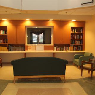 A cozy library interior featuring comfortable seating and shelves filled with books.