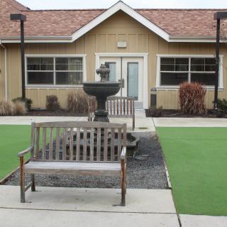 A courtyard with benches and a central fountain in front of a building.