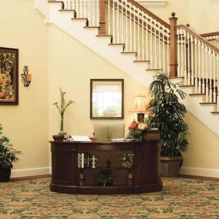 A cozy lobby area featuring a reception desk and staircase, adorned with plants and decor.