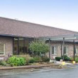 A brick building with a glass entrance and surrounding landscaping.
