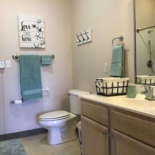 A clean, organized bathroom with teal towels and simple decor.