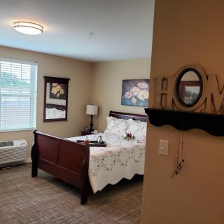 A cozy bedroom with a neatly made bed, wall art, and decorative elements.
