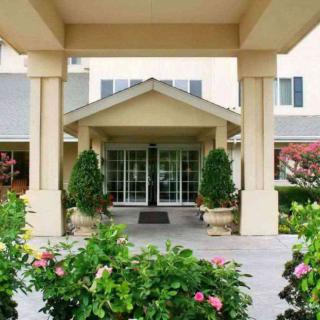 A welcoming entrance to a building surrounded by lush landscaping and colorful flowers.