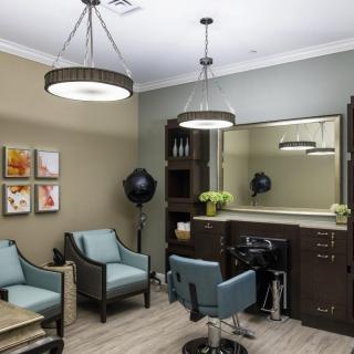 A modern salon interior featuring stylish seating, large mirror, and professional hair styling equipment.