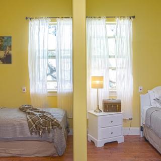A shared bedroom with a central partition dividing two beds, featuring yellow walls and soft lighting.