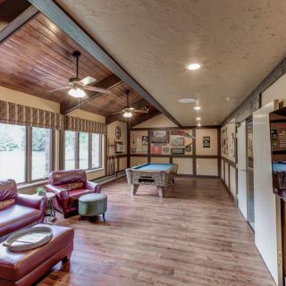 A cozy lounge with leather chairs, a pool table, and wooden flooring.