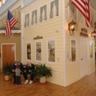 Indoor scene with a building facade, American flags, and people sitting on benches.