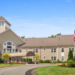 A large residential building with a driveway, surrounded by greenery and featuring an American flag.