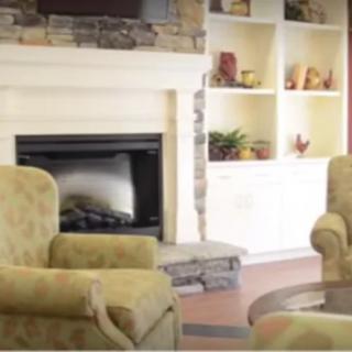 A cozy living room with armchairs and a fireplace, surrounded by built-in shelves.