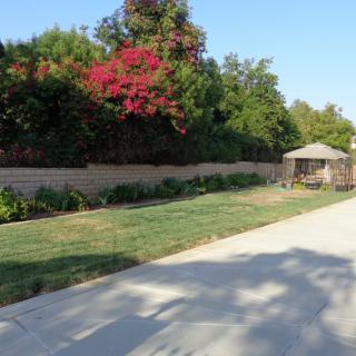 A peaceful garden scene with a gazebo and vibrant flowers lining a pathway.
