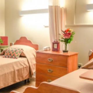 A cozy bedroom with two beds, a nightstand, and decorative flowers.
