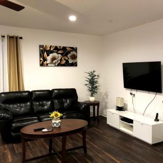 A cozy living room with a black leather sofa, wall-mounted television, and a wooden coffee table.