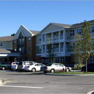 A residential building with a parking lot in front.