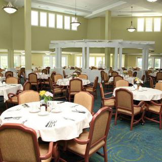 A spacious dining hall with neatly arranged tables and chairs, ready for guests.