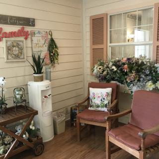 A cozy waiting room featuring two chairs, decorative flowers, indoor plants, and a water cooler.