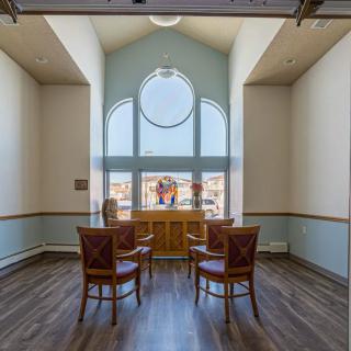 A well-lit interior space with four chairs arranged near a large window, showcasing elegant architecture and a hardwood floor.